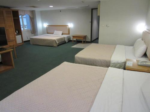 a hotel room with two beds and a television at Kenting City Gate Hotel in Hengchun