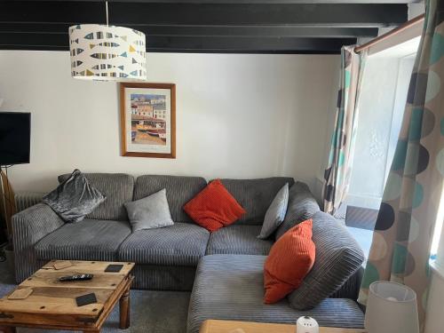 a living room with a gray couch with orange pillows at Cottage in village of Mevagissey Cornwall Sleeps 4 in Mevagissey