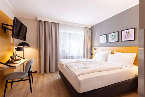 a hotel room with a bed and a desk and a television at Garner Hotel Cologne East by IHG in Cologne