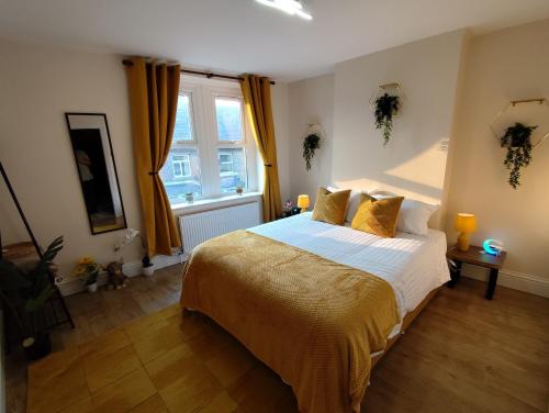 a bedroom with a bed with yellow sheets and a window at Peak District Cottage Sleeps 6, Parking and Projectors in all the Rooms in Buxton