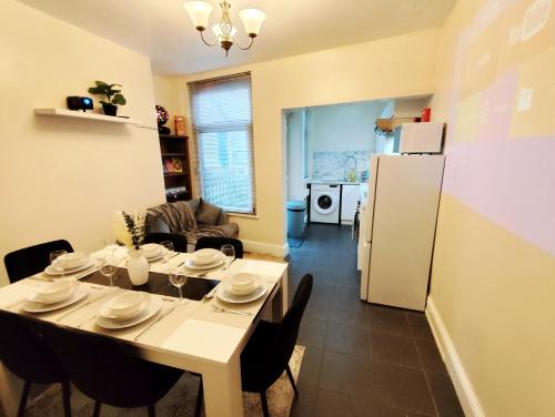 a kitchen and dining room with a table and a refrigerator at Peak District Cottage Sleeps 6, Parking and Projectors in all the Rooms in Buxton