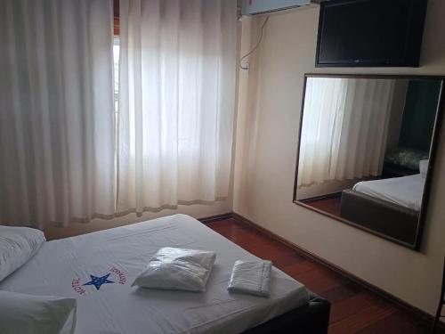 a hotel room with a bed and a mirror at Motel Antares in Porto Alegre