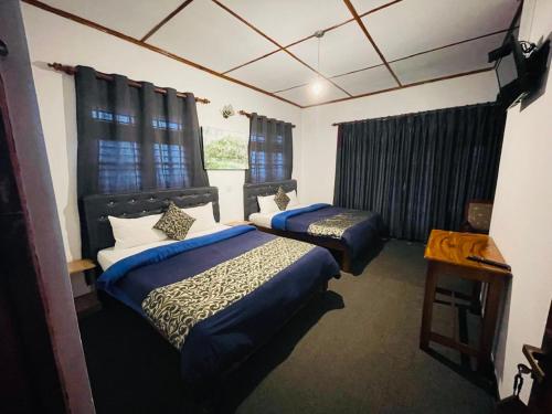 a hotel room with two beds and a window at New Royal Mount Hotel in Nuwara Eliya