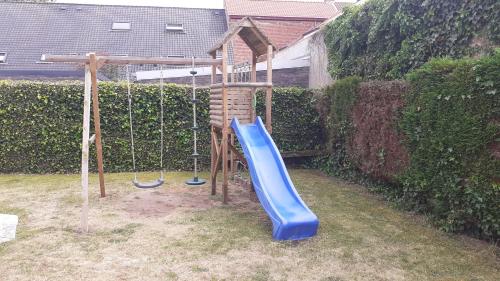 a playground with a blue slide in a yard at a l'aise aan zee in Koksijde