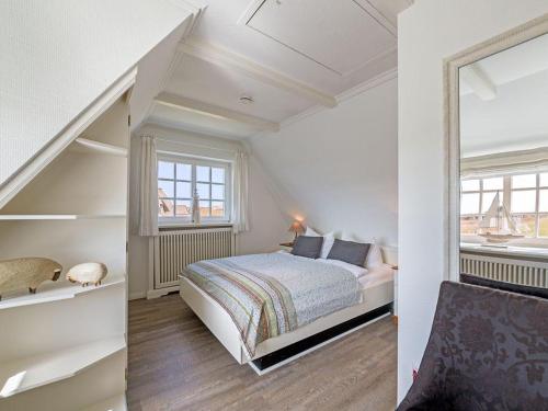 a white bedroom with a bed and a window at Leuchtturmblick-West in Kampen