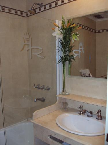 a bathroom with a sink and a vase of flowers at Hotel Rey in Buenos Aires