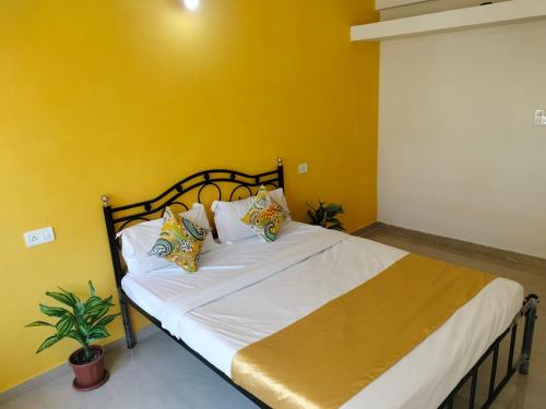 Bett in einem Zimmer mit gelber Wand in der Unterkunft Safron Modern Stay at Varca, Goa in Varca
