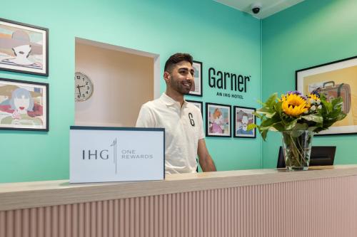 a man standing at a counter in a dermatologist office at Garner Hotel Cologne Porz - Airport by IHG in Cologne