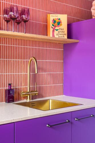 a kitchen with a sink and a purple wall at Lila-Licious in Breda