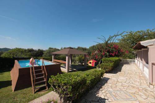 un patio trasero con piscina y sombrilla en FAMILY SWEET HOME IOANNA, en Karousádes