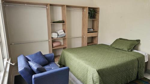 a bedroom with a bed and a blue chair at Anashe Home in Pretoria