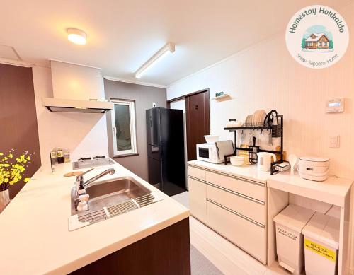 a kitchen with a sink and a black refrigerator at Snow Sapporo cozy house in Sapporo