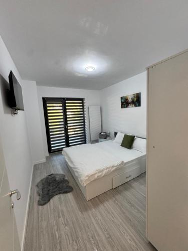 a white bedroom with a bed and a window at A B V Central Apartament in Râmnicu Vâlcea