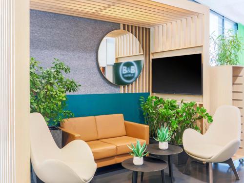 a waiting room with a couch and chairs and a mirror at B&B Hotel Aalen in Aalen