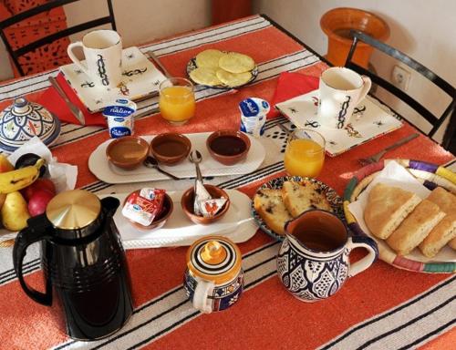 a table with breakfast foods and cups of orange juice at Riad restaurante Étoile dades Camping in Imdiazene