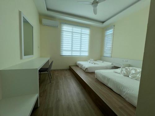 een slaapkamer met twee bedden, een bureau en een spiegel bij Kudat Golf View Villa in Kudat