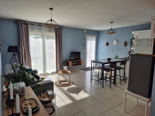 a living room with a table and a kitchen at Maison chaleureuse au calme in Domérat