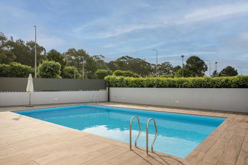 a swimming pool in a backyard with a white fence at GuestReady - Beach and Pool Escape in Gaia in Vila Nova de Gaia