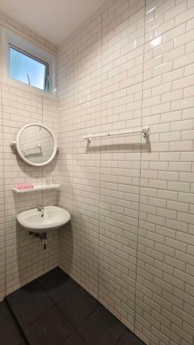 a white tiled bathroom with a sink and a mirror at Keerana Villa in Uttaradit