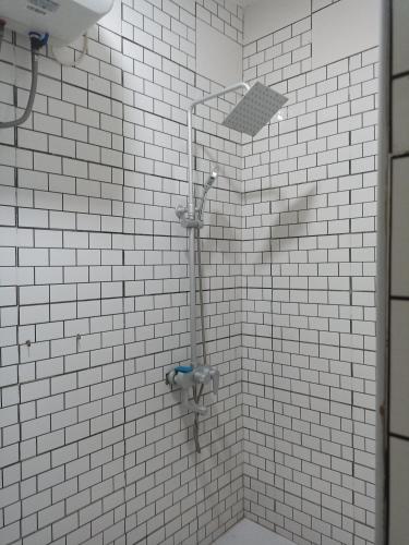 a shower in a bathroom with white tiled walls at Adelpha Properties,Abelenkpe accra in Abofu