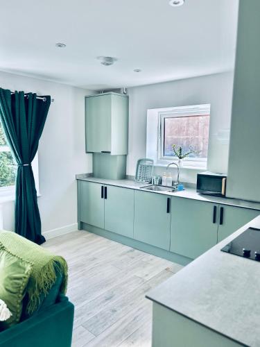 a kitchen with blue cabinets and a blue couch at Dover Ferry Apartments x 2 Sleeps 10 with parking and castle views in Kent