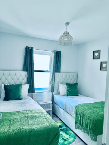 a bedroom with two beds with green sheets and a window at Dover Ferry Apartments x 2 Sleeps 10 with parking and castle views in Kent