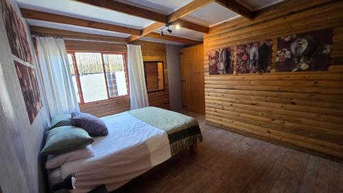 a bedroom with a bed in a room with wooden walls at Crescent Cottage Fish Hoek in Cape Town