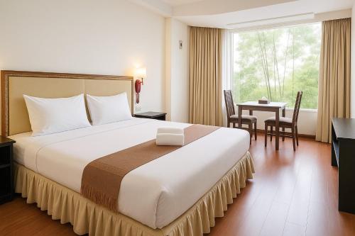 a hotel room with a large bed and a table at The Grand Imperial in Ban Song Hong
