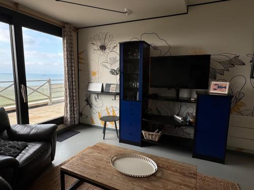 ein Wohnzimmer mit Fernseher, Couch und Tisch in der Unterkunft 2 Chambres face à la mer En terrasse La Naturelle in Wimereux