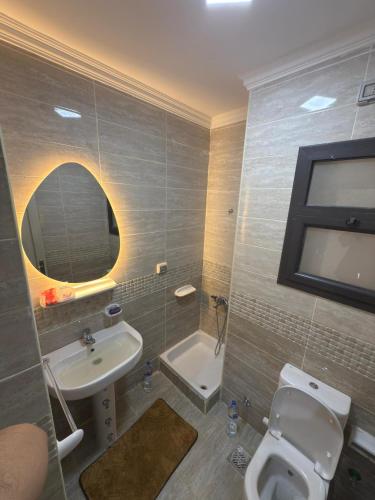 ein Badezimmer mit Waschbecken, Toilette und Spiegel in der Unterkunft مدينتي القاهرة الجديدة in Madinaty