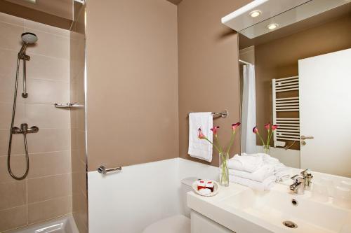 a white bathroom with a sink and a shower at Séjours & Affaires Paris-Vitry in Vitry-sur-Seine