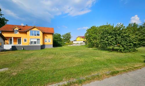une maison jaune avec une grande cour avec un champ herbeux dans l'établissement Idyllisches Ferienhaus Parndorf, à Parndorf
