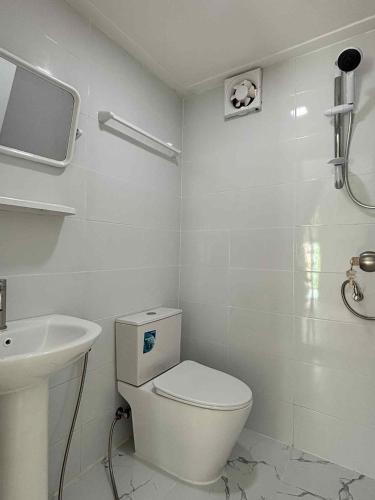 a white bathroom with a toilet and a sink at บ้านสวนแสงหล้า วิลล่า รีสอร์ท in Ban Nong Khayat