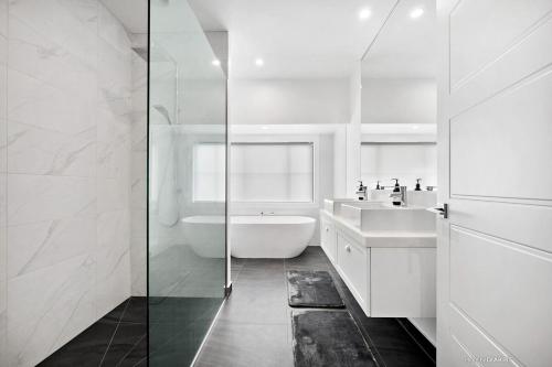 The WhiteHouse Te Whare Ma في مارتينبوره: حمام أبيض مع حوض استحمام ومغسلة