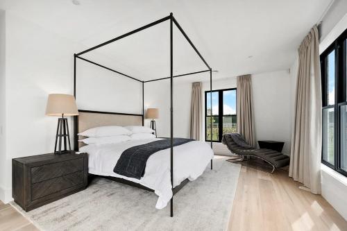 The WhiteHouse Te Whare Ma في مارتينبوره: غرفة نوم بيضاء مع سرير كبير وكرسي