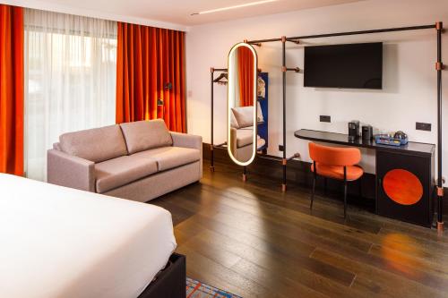 a hotel room with a bed and a couch and a tv at TRIBE Manchester Airport by Accor in Hale