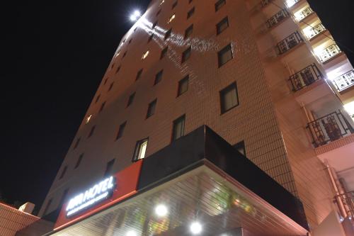 een hoog gebouw met een hotelbord ervoor bij APA Hotel Miyazaki Miyakonojo Ekimae in Miyakonojo
