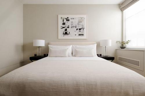 a white bedroom with a large bed with two lamps at Comfortable Luxury apartments near the Center - London in Solihull