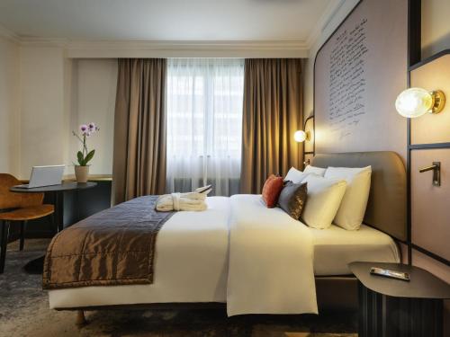 Una habitación de hotel con una cama grande y un escritorio. en Mercure Versailles Paris Ouest, en Versalles