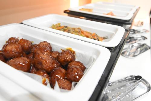 two trays of meatballs and other food on a counter at APA Hotel Miyazaki Miyakonojo Ekimae in Miyakonozyō