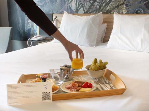 a tray with a plate of food on a bed at Novotel Narbonne Sud A9/A61 in Narbonne