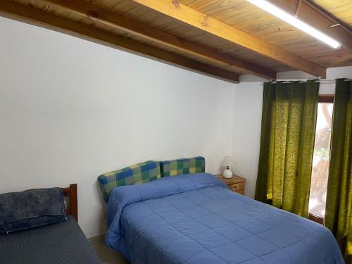 Un dormitorio con una cama azul y una ventana. en Departamento en Mar Chiquita, en Balneario Mar Chiquita
