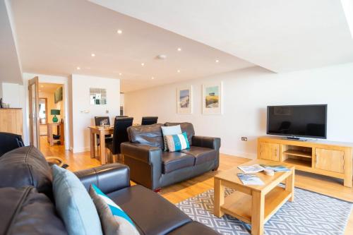 a living room with a couch and a tv at Fistral Beach Garden Apartment 3 in Newquay