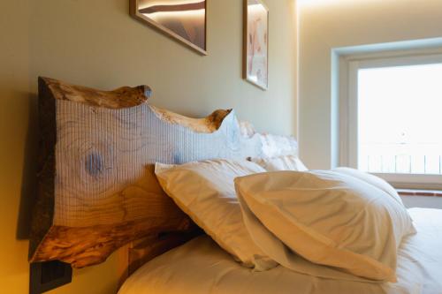 a bed with white pillows and a wooden head board at Corte Bonfiglio Colombari in Illasi