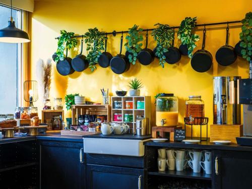 eine Küche mit Töpfen und Pfannen, die an der Wand hängen in der Unterkunft Novotel Saint Avold in Saint-Avold