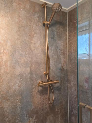 a shower with a shower head on a wall at Chalet Dune chaletpark krabbenkreek Sint Annaland in Sint Annaland