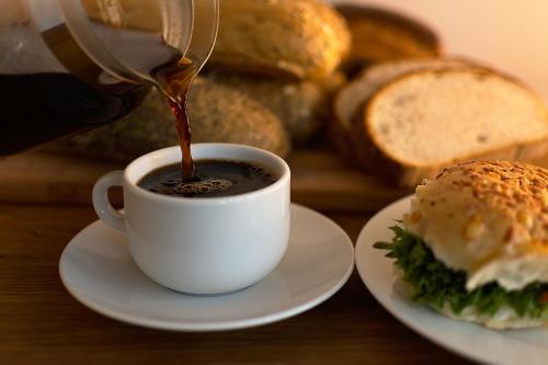 a person is pouring coffee into a cup next to a sandwich at Hôtel Restaurant Brasilia in Cagnes-sur-Mer