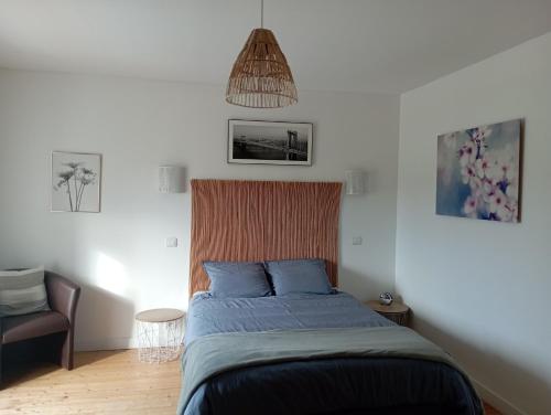 a bedroom with a bed with blue sheets and a chair at Le Cosy in Hiersac