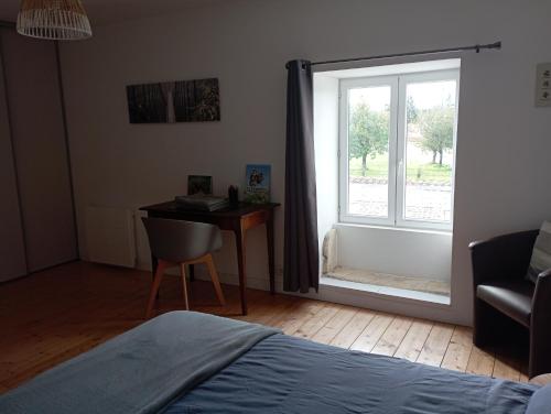 a bedroom with a bed and a desk and a window at Le Cosy in Hiersac