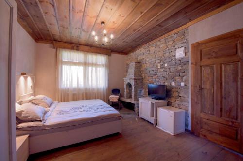 1 dormitorio con cama y pared de piedra en Leshten Guest Homes, en Leshten